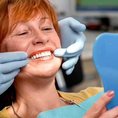Lady seeing her smile in the handheld mirror