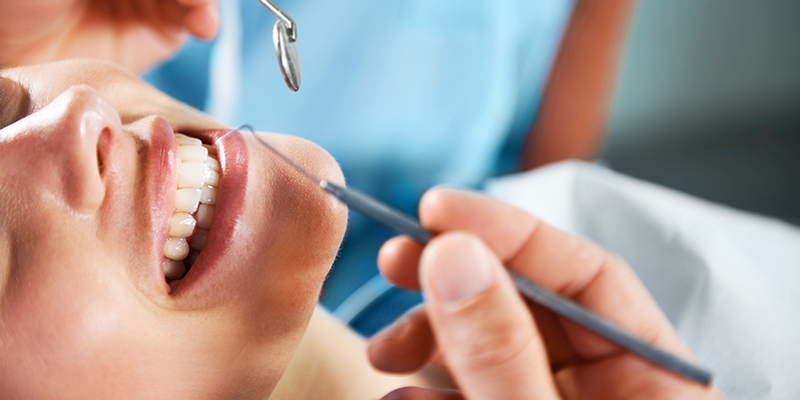 Lady smiling while her teeth are getting checked out