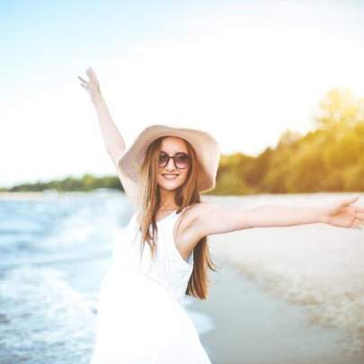 happy-smiling-woman-free-happiness-bliss-ocean-beach-standing-with-hat-sunglasses-rasing-hands-portrait-multicultural-female-model-white-summer-dress-enjoying-nature_665183-22320